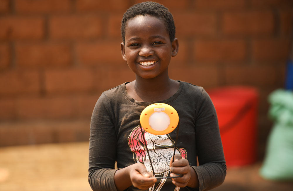 A child smiles while examining a solar study kit. © UNICEF/UN0413673/Chikondi