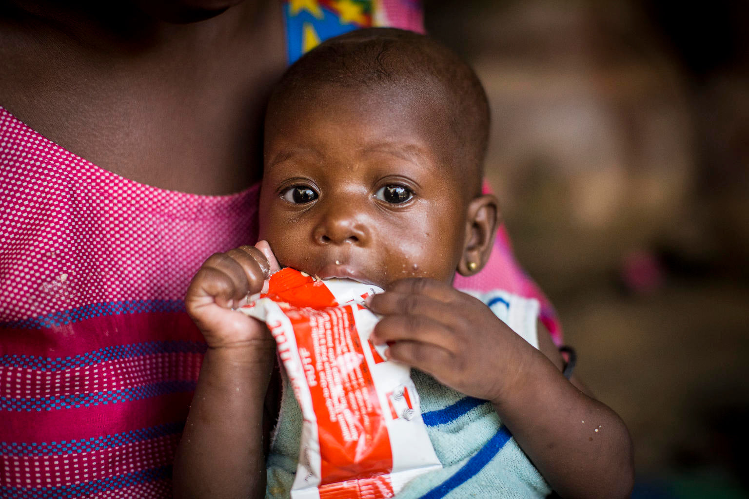 Baby eating therapeutic Plumpy Nut sachet  © UNICEF/UNI287192/Dicko