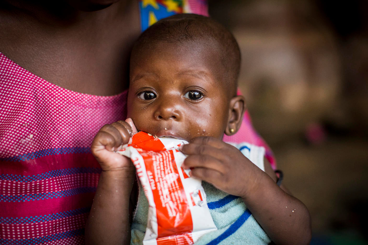 Baby eating therapeutic Plumpy Nut sachet © UNICEF/UNI287192/Dicko