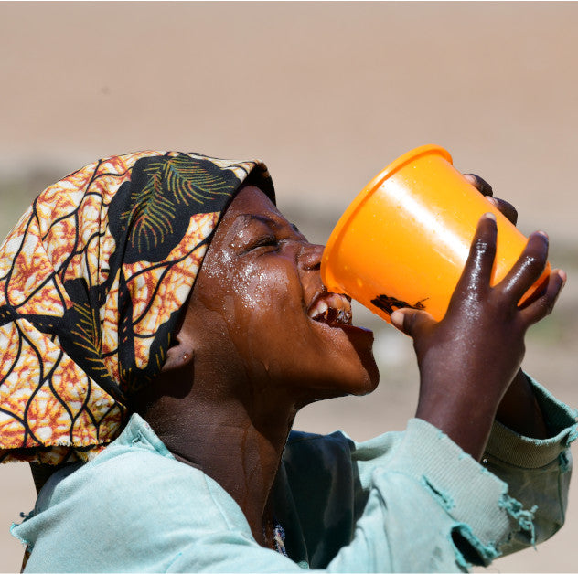 A child drinks water from a bucket