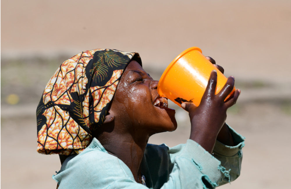 A child drinks water from a small bucket. © UNICEF/UN0469332/Dejongh