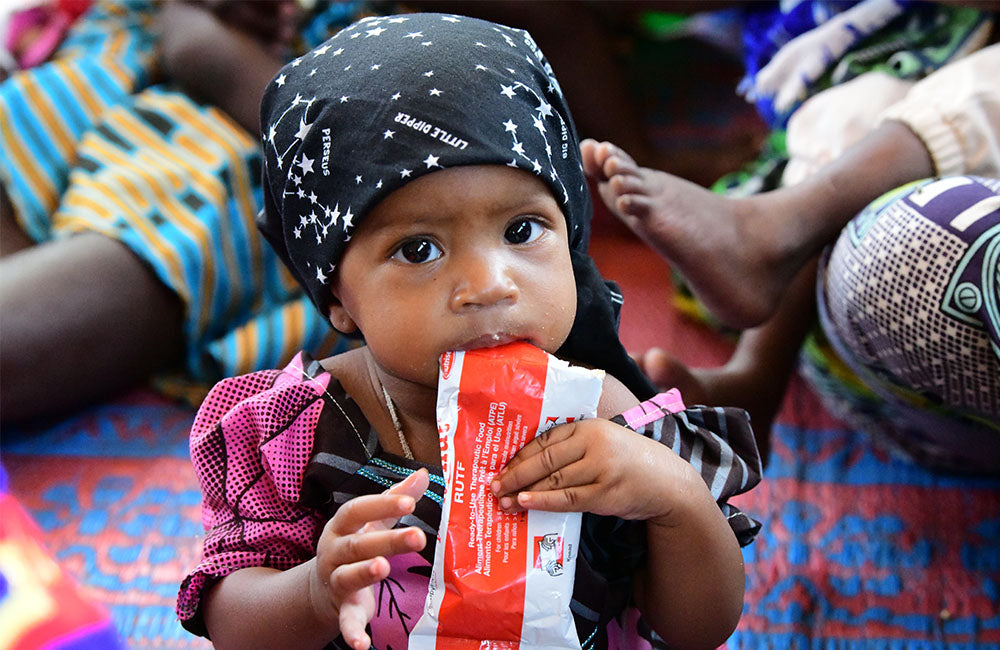 A child eats from a Ready-to-Use Therapeutic Food that provides essential nutrients for survival and growth. © UNICEF/UN0469311/Dejongh