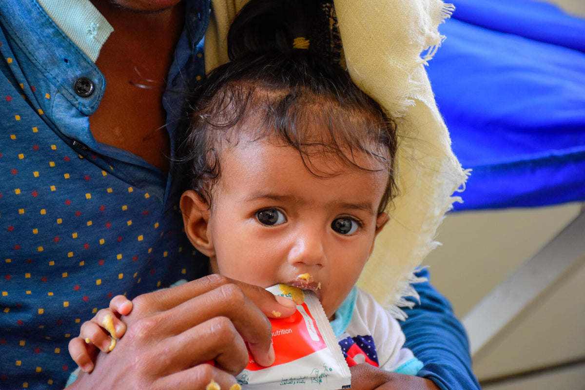 Young child eating therapeutic Plumpy’Nut peanut butter. © UNICEF/UN0670775/Gabreez